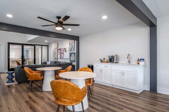A modern dining room with a white table and orange chairs.