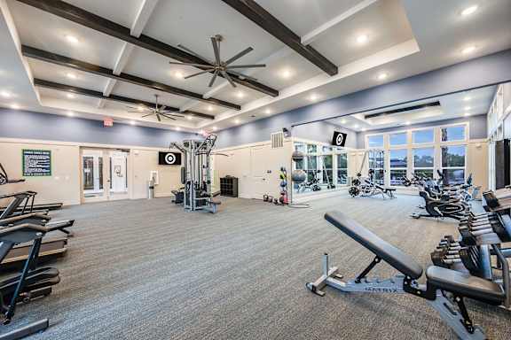 A gym with a variety of equipment including treadmills, weights, and exercise machines.