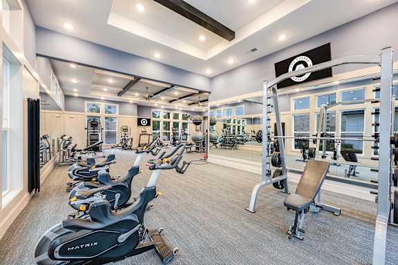 A gym with a variety of exercise equipment including treadmills, stationary bikes, and weight machines.