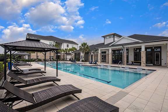 A pool area with sun loungers and a pavilion.