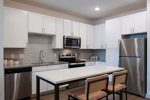 A kitchen with a table and chairs in front of a refrigerator.