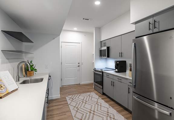 an open kitchen with stainless steel appliances and white countertops