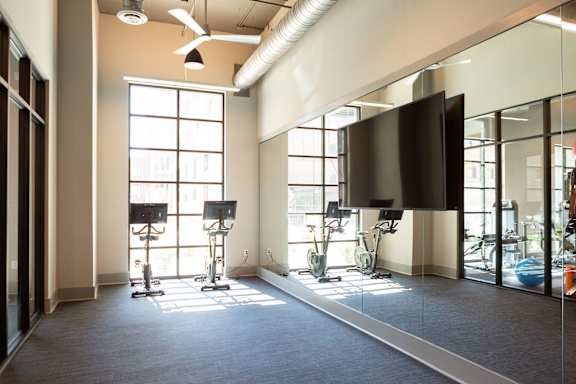 A gym with a television and exercise equipment.