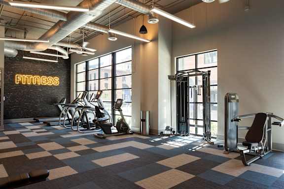 A fitness room with a variety of equipment including a treadmill, weights, and a bench.