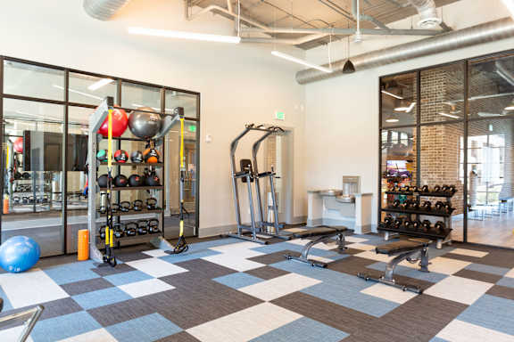 A gym with a variety of equipment including weights, a bench, and a ball.
