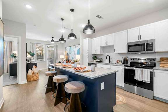 A modern kitchen with a dark blue island and white cabinets.