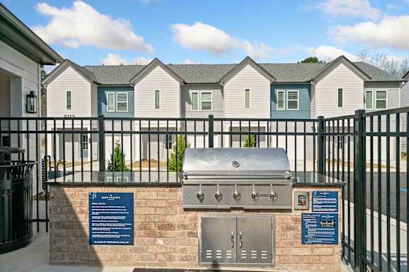 A row of houses with a grill and information board in front.