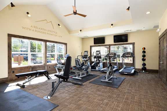 A gym with a variety of equipment including treadmills, weights, and a bench.