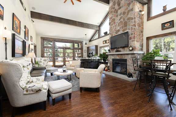 A living room with a stone fireplace and a flat screen TV mounted above it.