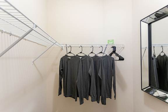 A row of black shirts hanging on a rack in a store.