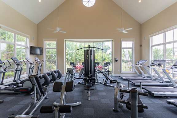 A gym with treadmills, exercise bikes, and a television.