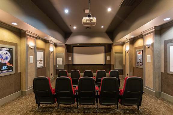 A movie theater with red seats and a screen.