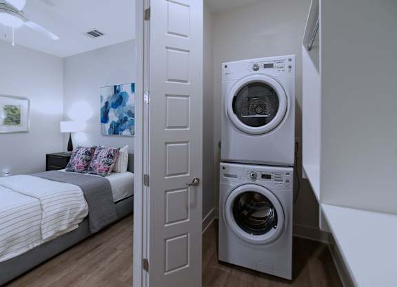 A washer and dryer in a small room with a bed.