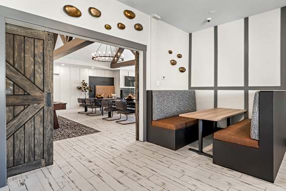 A modern dining room with a wooden floor and a large wooden door.