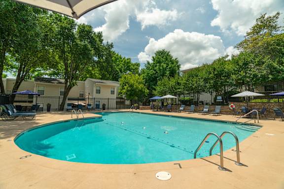 A large outdoor swimming pool surrounded by trees and lounge chairs.