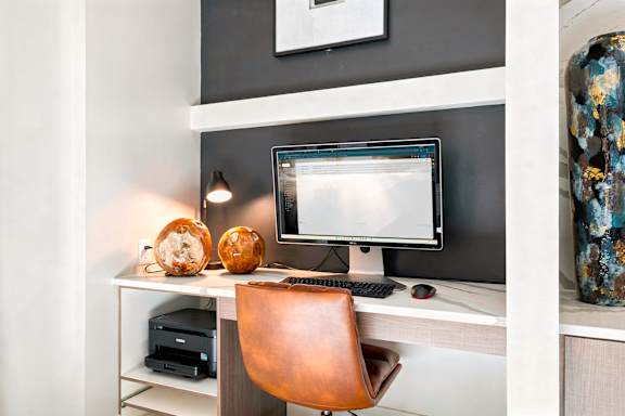 A computer desk with a monitor, keyboard, and mouse.