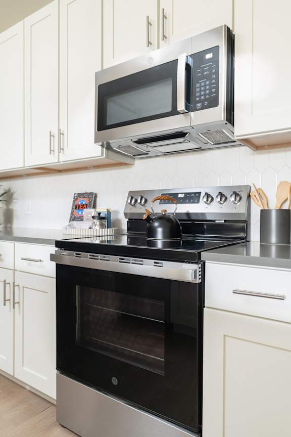 A modern kitchen with a stainless steel oven and microwave above it.