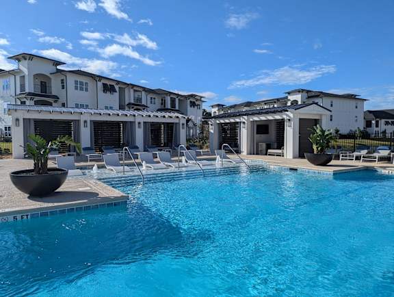 A large swimming pool in front of a white building with a black roof.