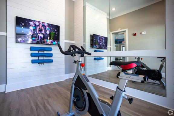 a gym with a bike and a flat screen tv