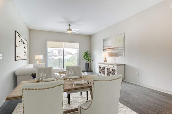 A dining room with a table set for two and a ceiling fan.