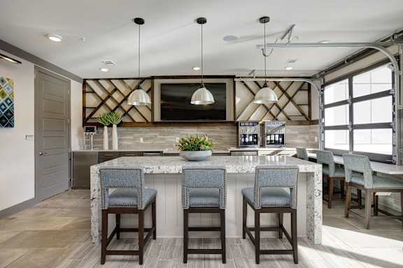 A kitchen with a marble island and bar stools.