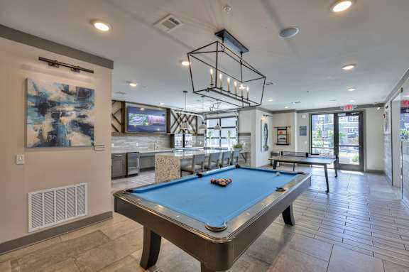 A pool table in a room with a TV and a painting on the wall.