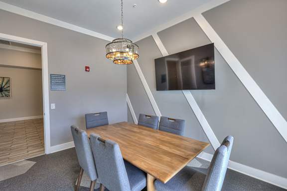 A dining room with a wooden table and grey chairs.