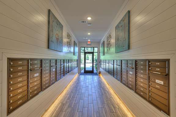 A hallway with a series of mailboxes on the wall and a door at the end.