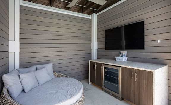 A cabana with a chair, a cabinet, and a TV.
