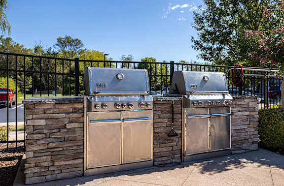 Two stainless steel grills are attached to a stone wall.