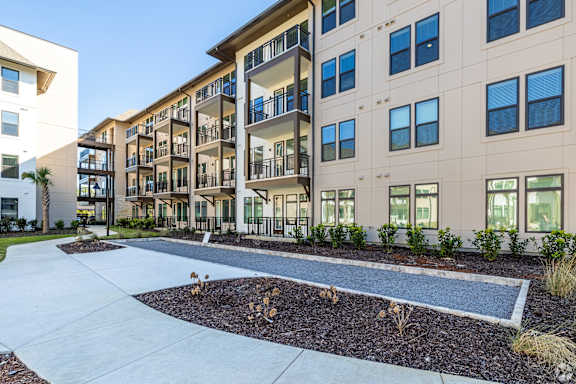 A modern apartment complex with a landscaped courtyard in the foreground.