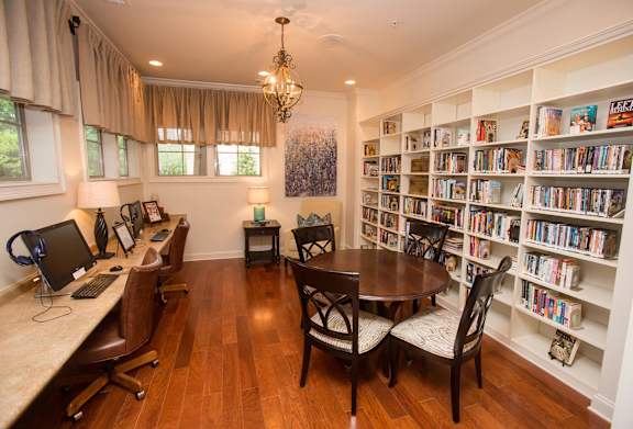 A room with a desk, chairs, and a bookshelf filled with books.
