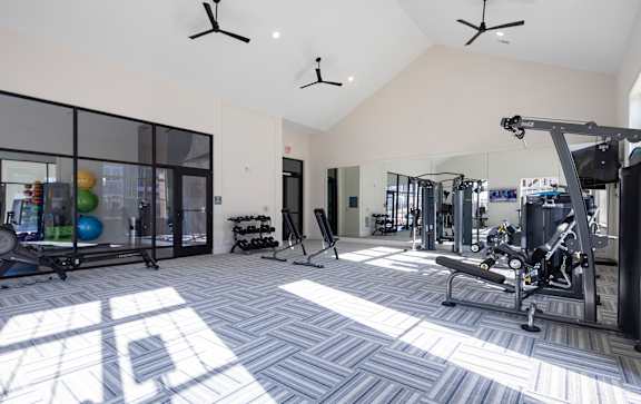 A spacious gym with a variety of equipment and a large mirrored wall.