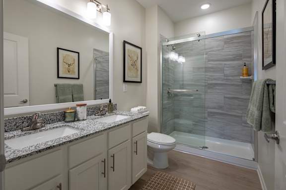 A bathroom with a glass shower stall and a toilet.