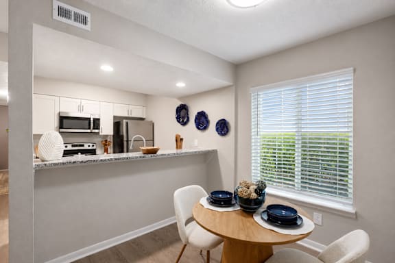 A kitchen with a table and chairs by a window.