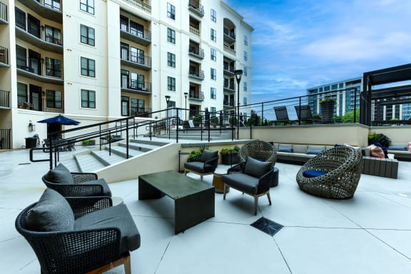 a patio with chairs and a coffee table in front of an apartment building