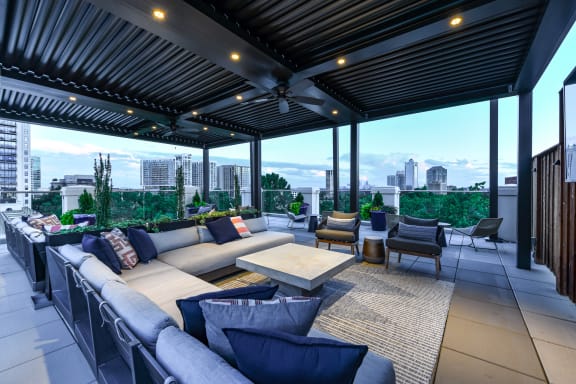 an outdoor living room with a pergola and a city skyline in the background