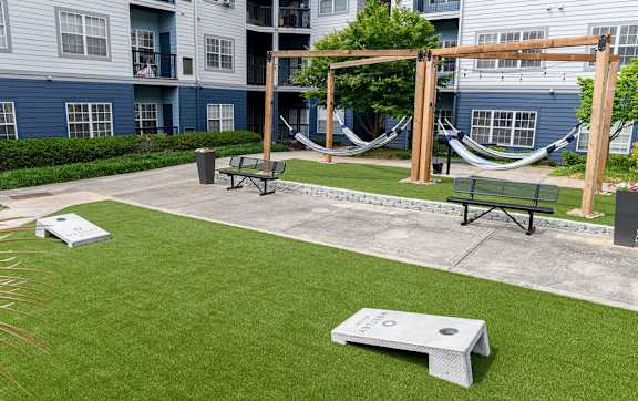 A hammock is suspended between two wooden posts in a grassy courtyard.