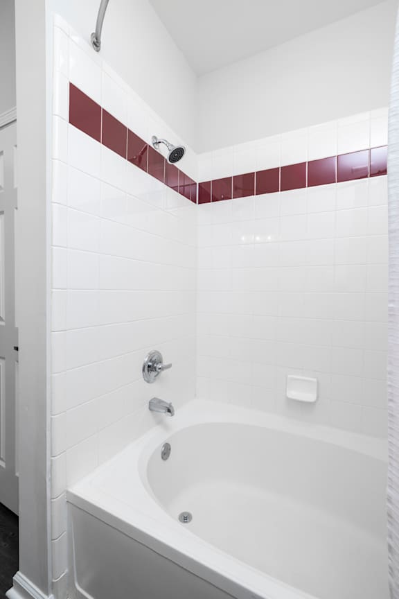 A white bathtub with a shower head above it.