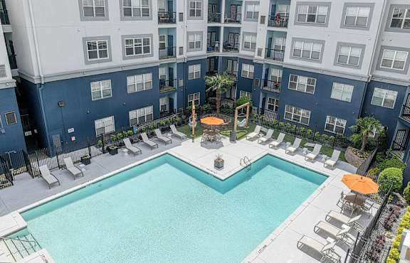 A large swimming pool surrounded by lounge chairs and umbrellas.