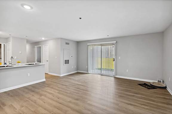 A spacious room with wooden flooring and white walls.
