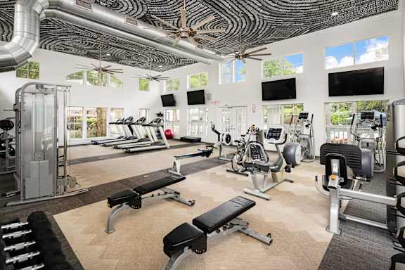 A gym with a variety of equipment including treadmills, weights, and exercise machines.