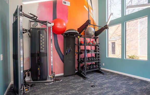 A gym room with a pink and orange wall and a variety of equipment.