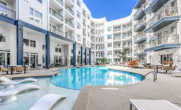 A swimming pool in the middle of a courtyard surrounded by white buildings.