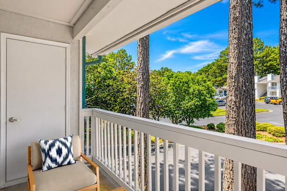 A balcony with a chair and a pillow overlooking a street.