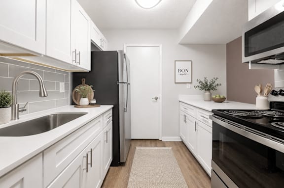 A kitchen with white cabinets and a black refrigerator.