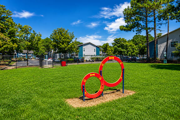 A red sculpture of two interlocking rings sits in a grassy field.