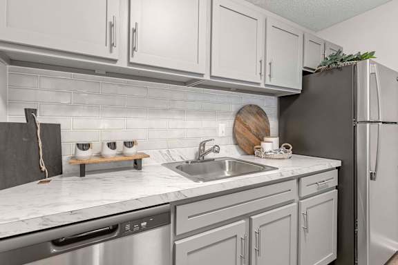 A kitchen with a black refrigerator and white cabinets.