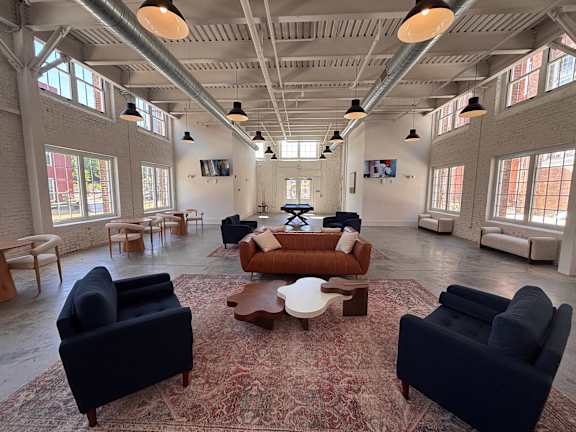 A large room with a rug and several chairs.