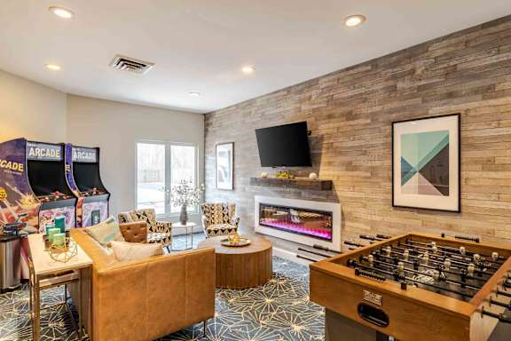 A room with a foosball table, couches, and a television.